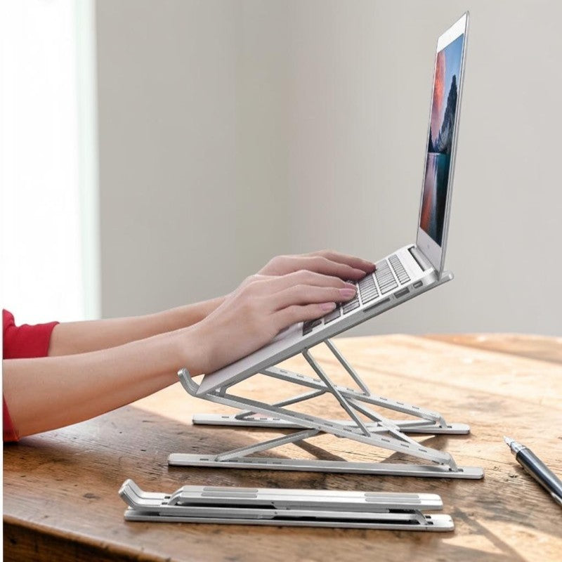 Doctor Desk silver aluminium laptop stand holding a laptop on a wooden desk with a folded unit in the foreground