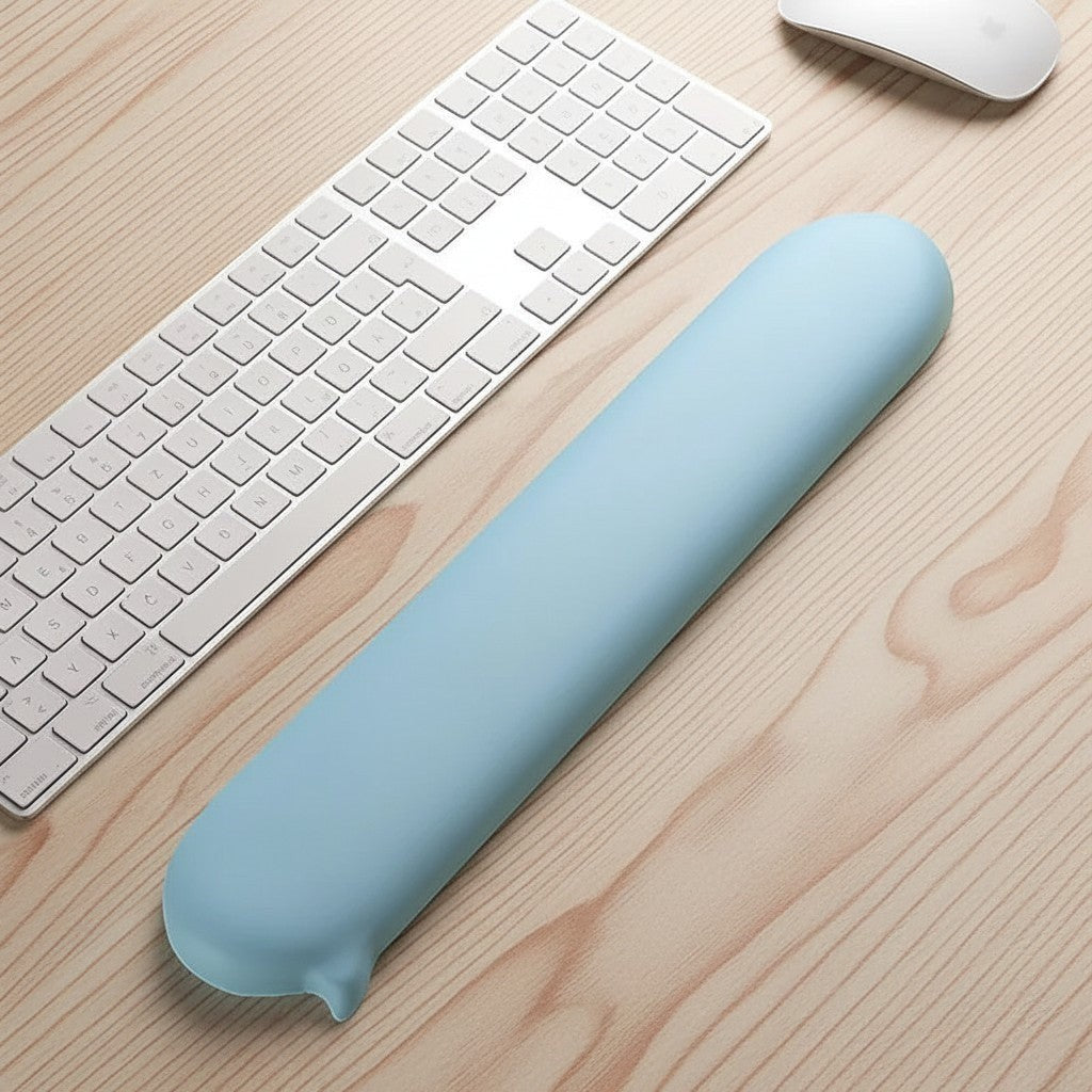 Doctor Desk blue silicone ergonomic wrist rest on a wooden desk next to a white keyboard.