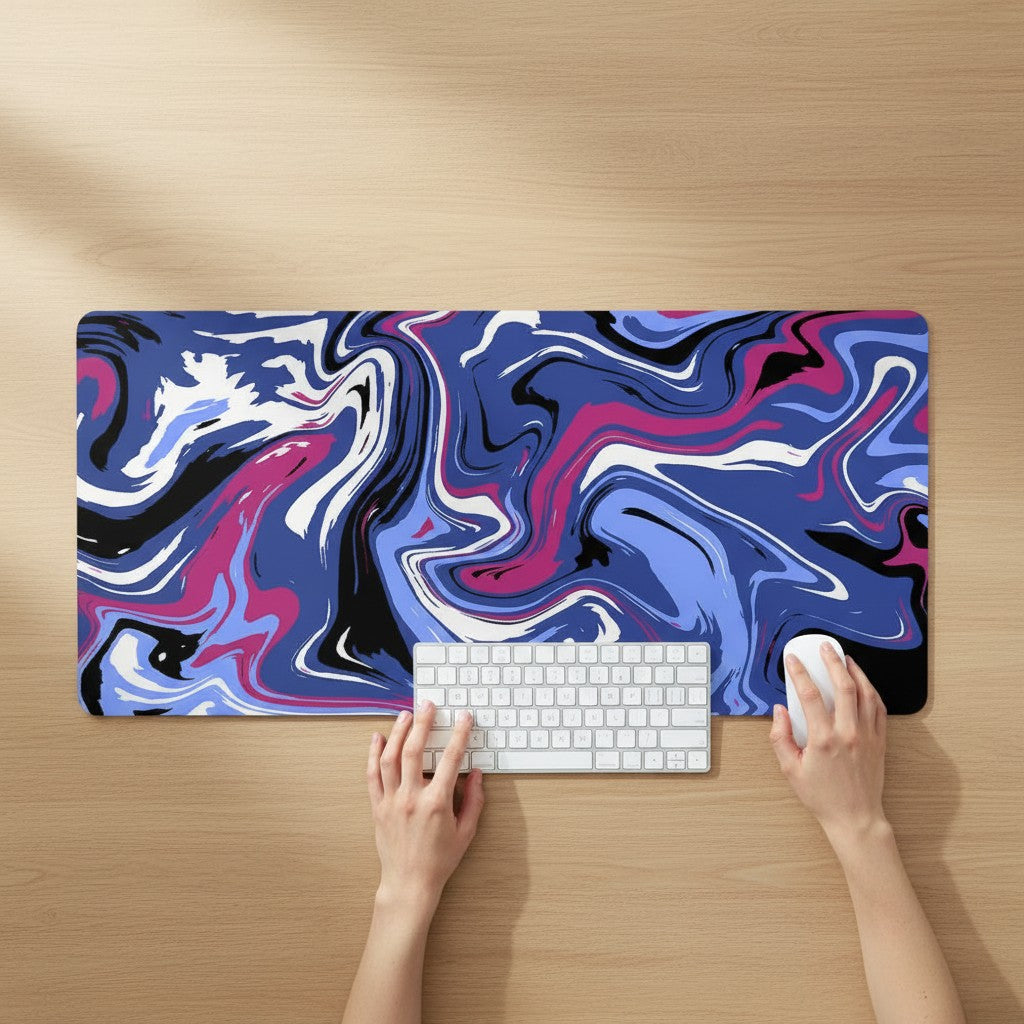 Doctor Desk XXL desk mat with blue, pink, and black liquid swirl pattern, featuring stitched edges on a wooden desk.