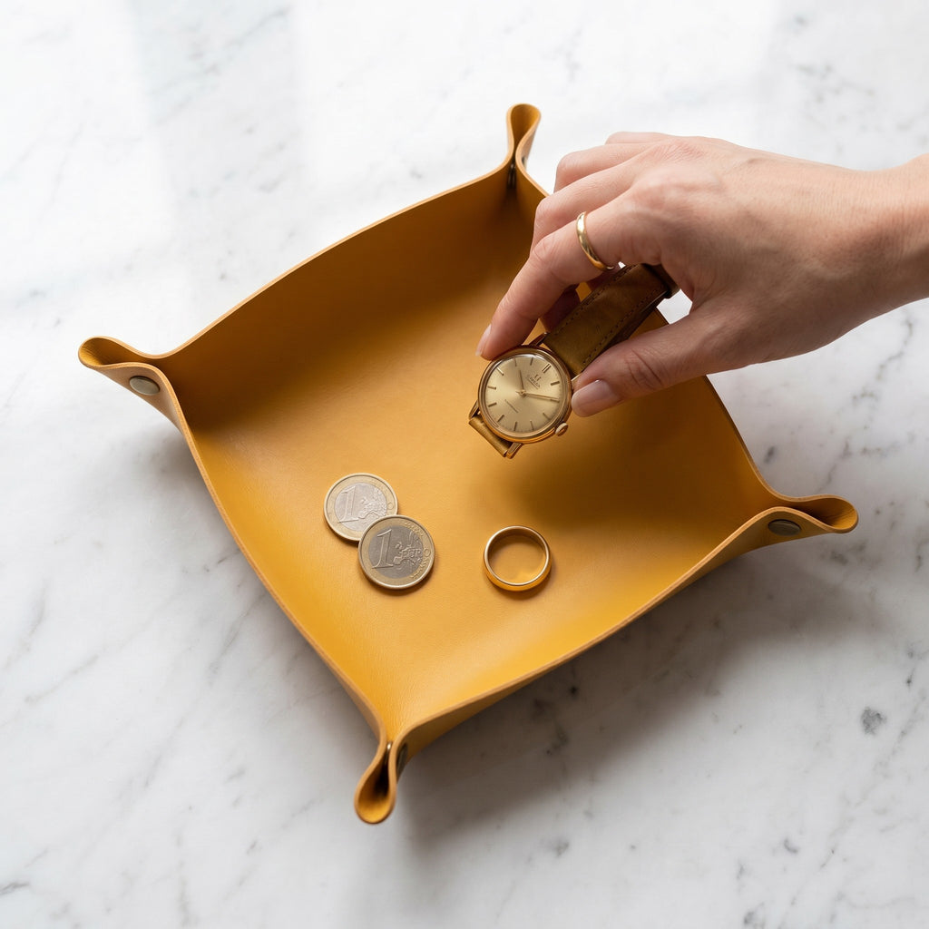 Doctor Desk mustard yellow PU leather foldable valet tray holding a gold watch, coins, and a ring on marble surface