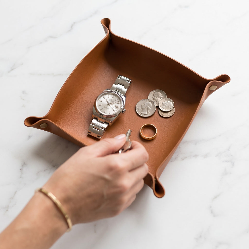 Doctor Desk tan PU leather foldable valet tray holding a watch, coins, and a ring on a marble surface